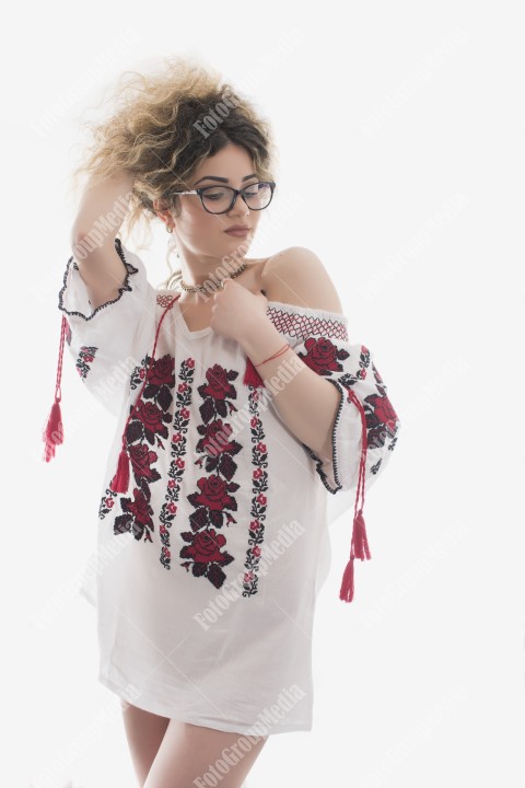 Woman with curly hair and white dress with red flowers posing on white background