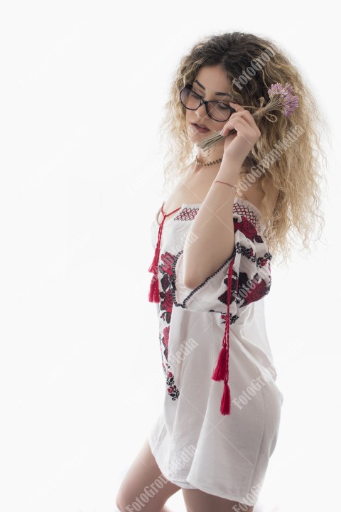 Woman with curly hair and white dress with red flowers posing on white background