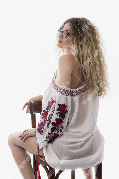 Woman with curly hair and white dress with red flowers posing on white background