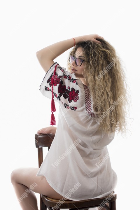 Woman with curly hair and white dress with red flowers posing on white background