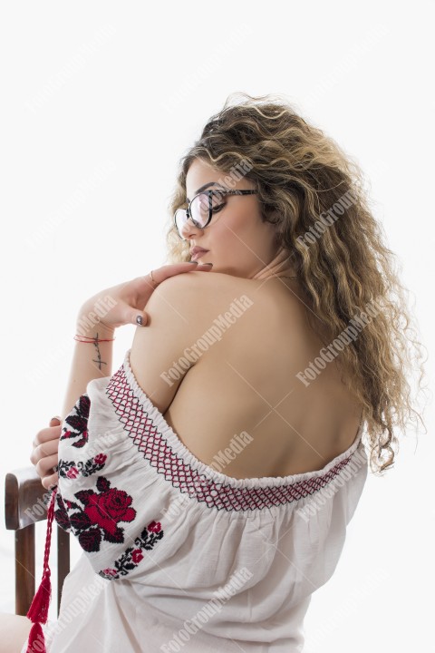 Woman with curly hair and white dress with red flowers posing on white background