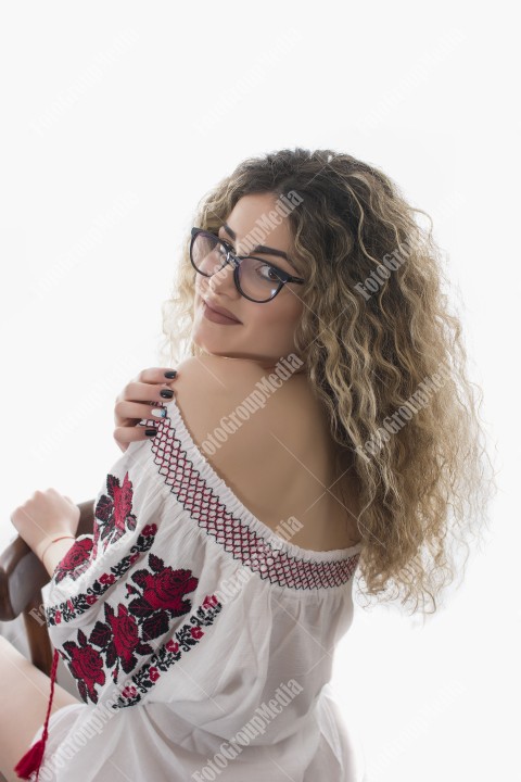 Woman with curly hair and white dress with red flowers posing on white background
