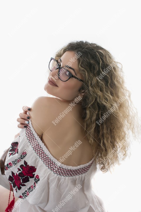 Woman with curly hair and white dress with red flowers posing on white background