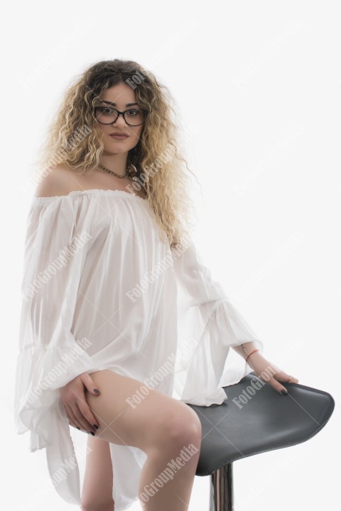Woman with curly hair and white dress posing on white background