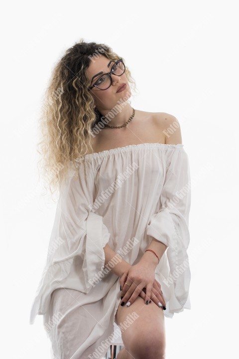 Woman with curly hair and white dress posing on white background