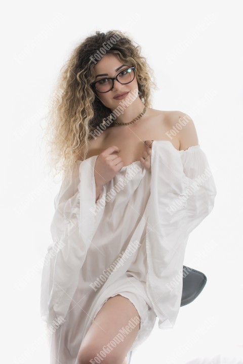 Woman with curly hair and white dress posing on white background
