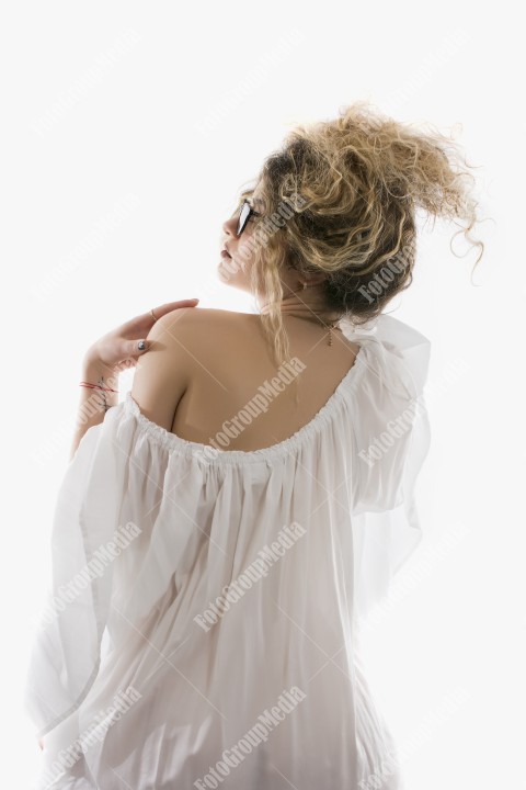 Woman with curly hair and white dress posing on white background