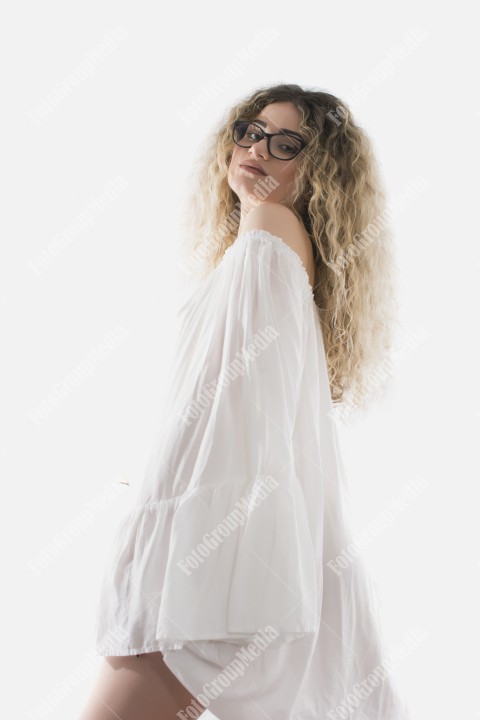 Woman with curly hair and white dress posing on white background