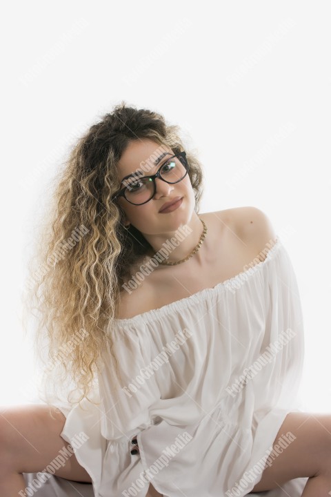 Woman with curly hair and white dress posing on white background