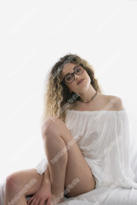 Woman with curly hair and white dress posing on white background