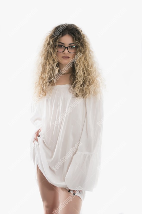 Woman with curly hair and white dress posing on white background