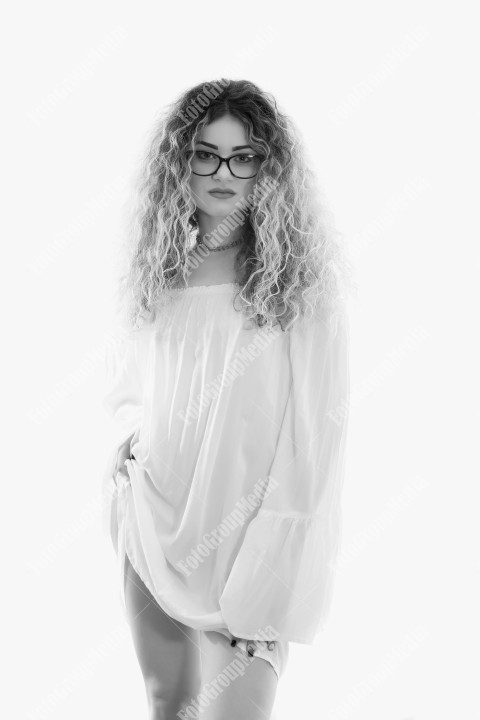 Woman with curly hair and white dress posing on white background