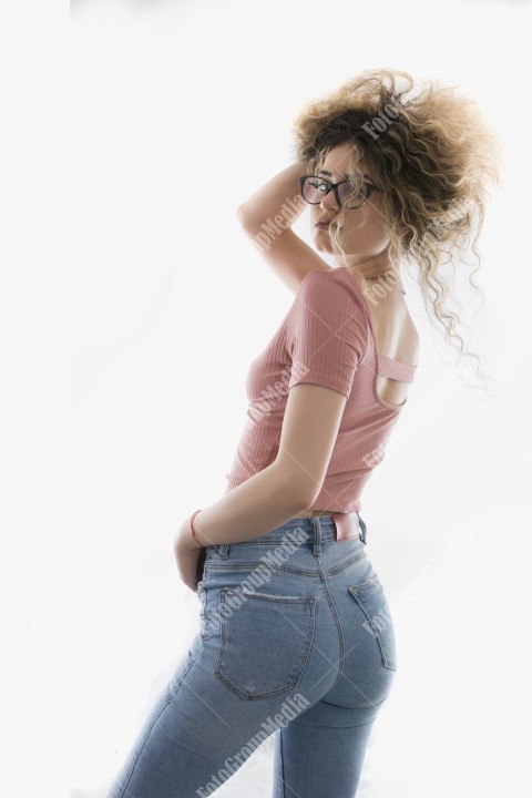 Woman with curly hair posing in t-shirt and jeans on white background