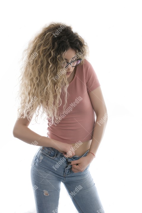 Woman with curly hair posing in t-shirt and jeans on white background