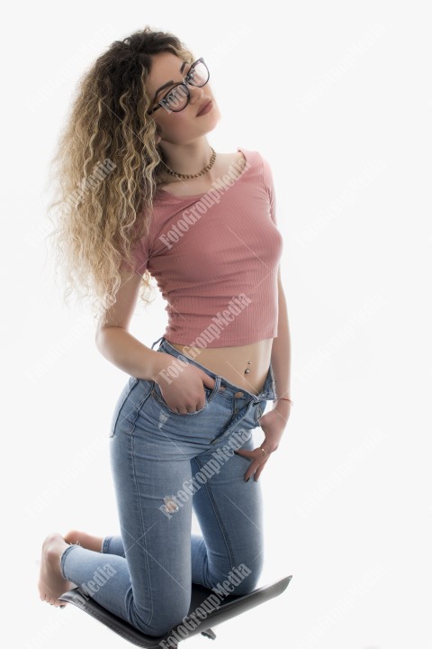 Woman with curly hair posing in t-shirt and jeans on white background