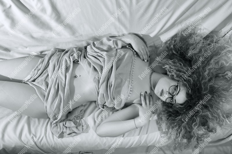 Woman with curly hair wrapped in a scarf posing on bed