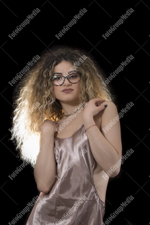 Woman with curly hair and satin lingerie posing on black background