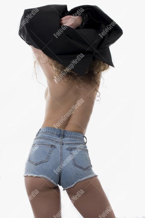 Woman with curly hair dressed in jeans and black jacket posing on white background