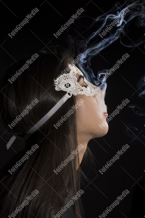Close-up portrait of a young girl with lace mask and smoking