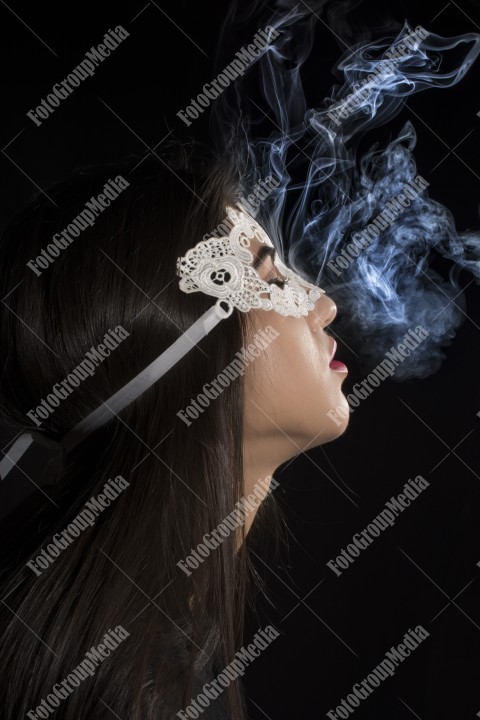 Close-up portrait of a young girl with lace mask and smoking