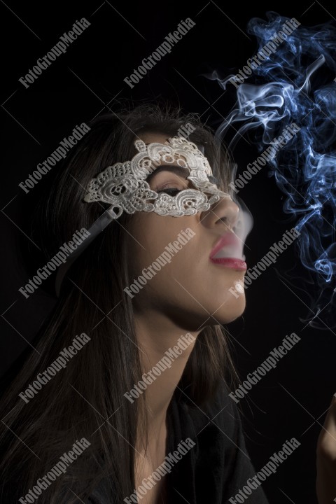 Close-up portrait of a young girl with lace mask and smoking