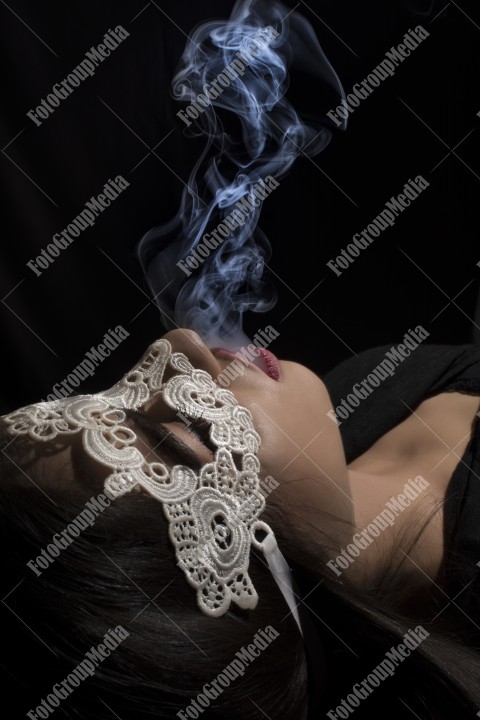Close-up portrait of a young girl with lace mask and smoking