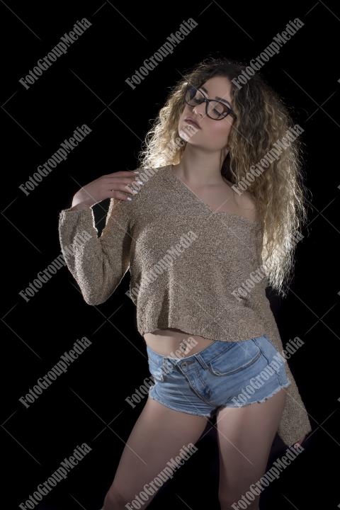 A confident young woman poses casually, studio shot