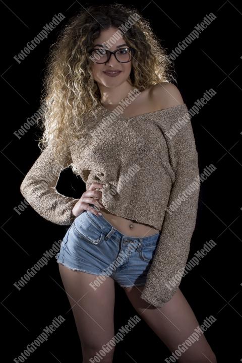A confident young woman poses casually, studio shot
