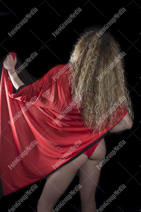 Mysterious figure draped in a bold red cape, studio shot