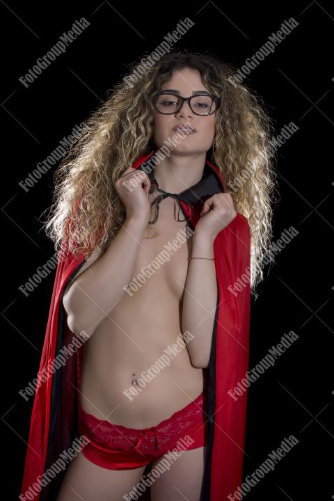 Mysterious figure draped in a bold red cape, studio shot