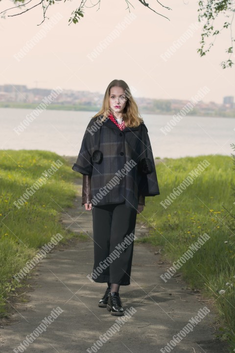 Blond girl posing near lake shore in a cold spring day