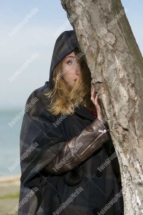 Blue eyed girl hiding behind a tree