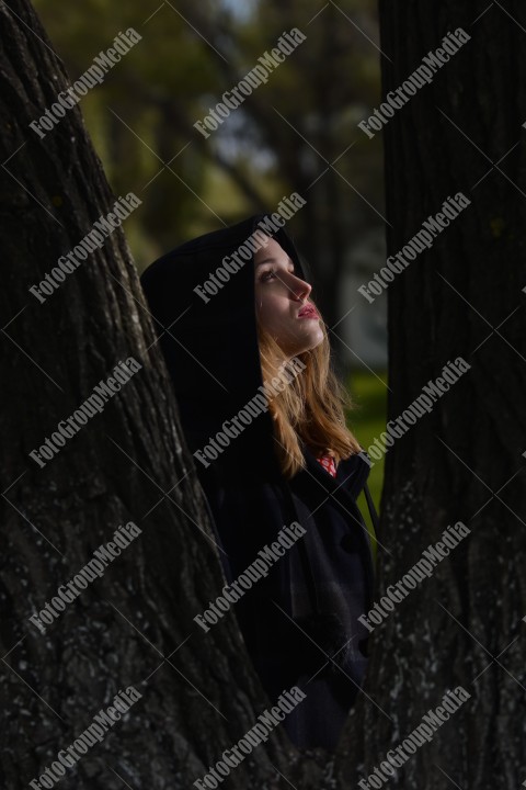 Young girl hiding behind tree trunk