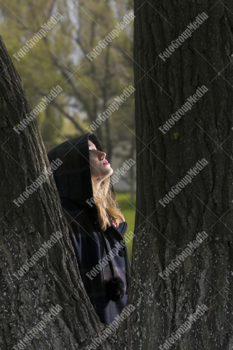 Young girl hiding behind tree trunk