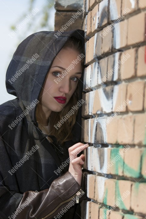 Beautiful blond girl with blue eyes posing near a brick wall