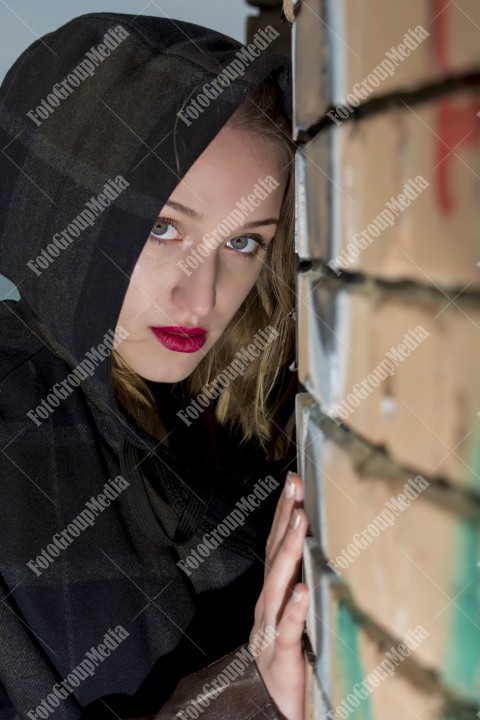 Beautiful blond girl with blue eyes posing near a brick wall