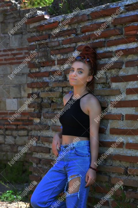 Redhead with blue eyes posing outdoor near a brick wall