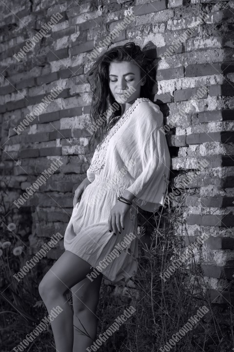 Redhead with blue eyes posing outdoor near a brick wall