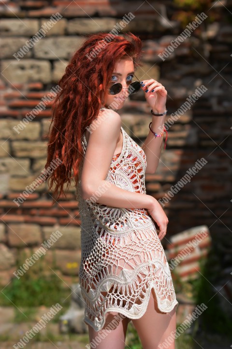 Beautiful redhead young woman in a stylish summer knit clothes posing outdoor