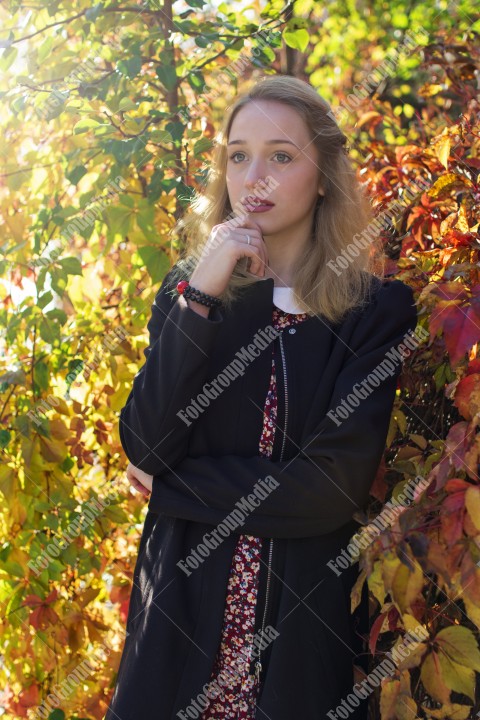 Blond girl posing in autumn day on colorful leafs background