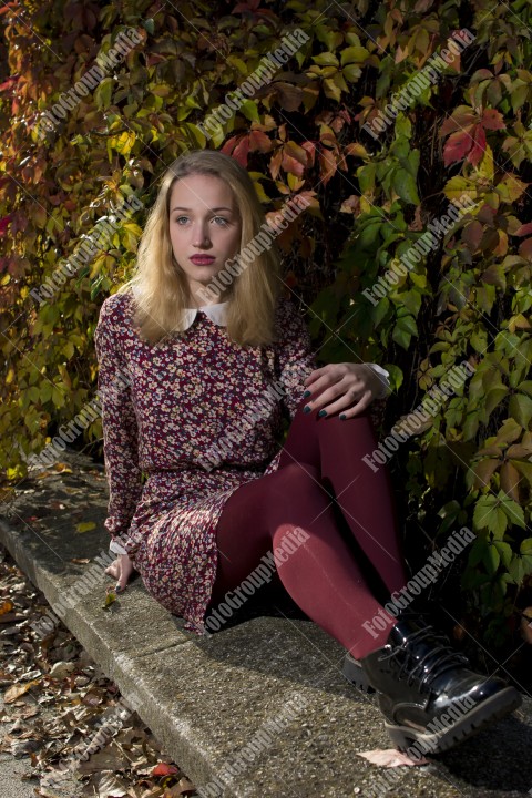 Blond girl posing in autumn day on colorful leafs background