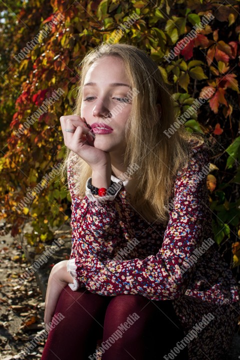 Blond girl posing in autumn day on colorful leafs background