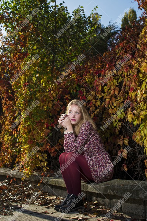 Blond girl posing in autumn day on colorful leafs background