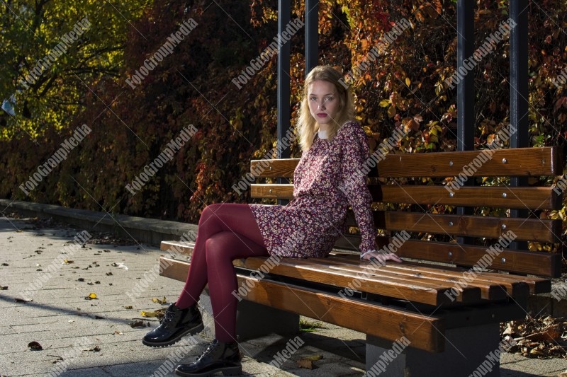 Blond girl posing in autumn day on bench