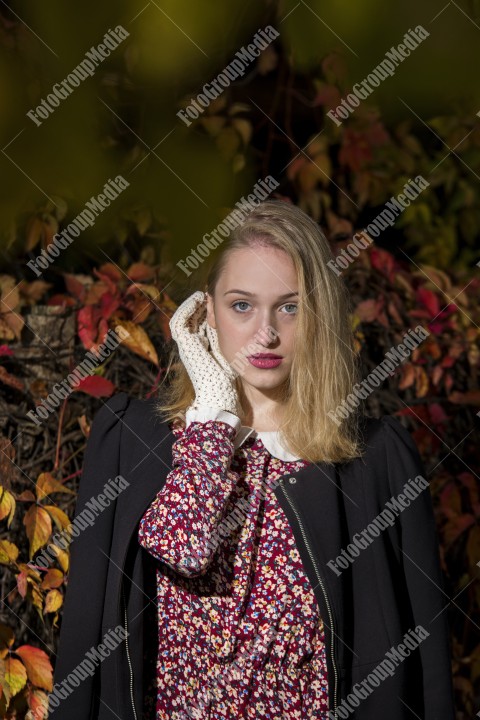 Blond girl posing in autumn day on colorful leafs background