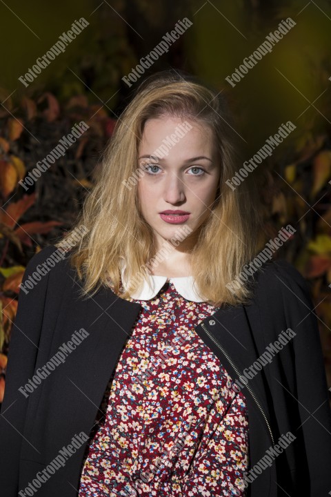 Blond girl posing in autumn day on colorful leafs background