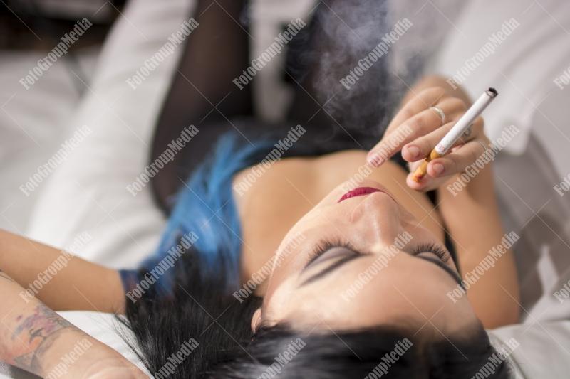 Young woman lounges with a cigarette on a plush sofa
