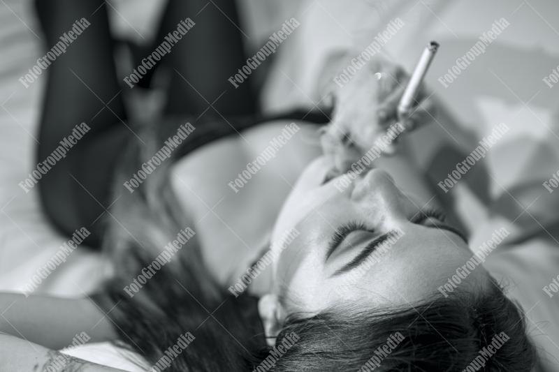 Young woman lounges with a cigarette on a plush sofa