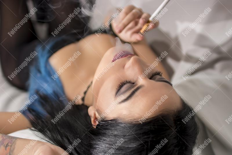 Young woman lounges with a cigarette on a plush sofa