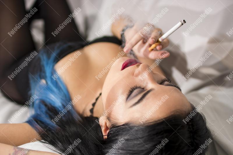 Young woman lounges with a cigarette on a plush sofa